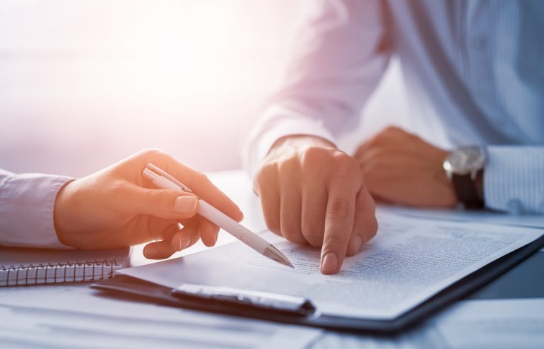 Business people negotiating a contract. Human hands working with documents at desk and signing contract.